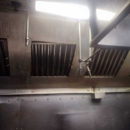 Stainless steel restaurant extraction hood and ventilation system being degreased for fire safety in Galway.