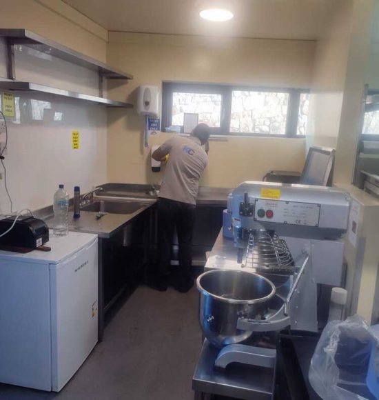 Professional cleaner scrubbing restaurant kitchen sinks and walls in Galway to remove grease and grime.